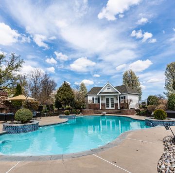 swimming pool with parasol, tables, and chairs