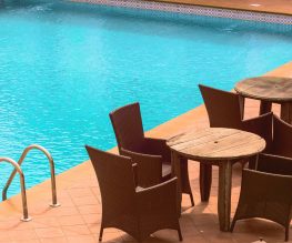 wooden cafe table and chairs beside inground pool
